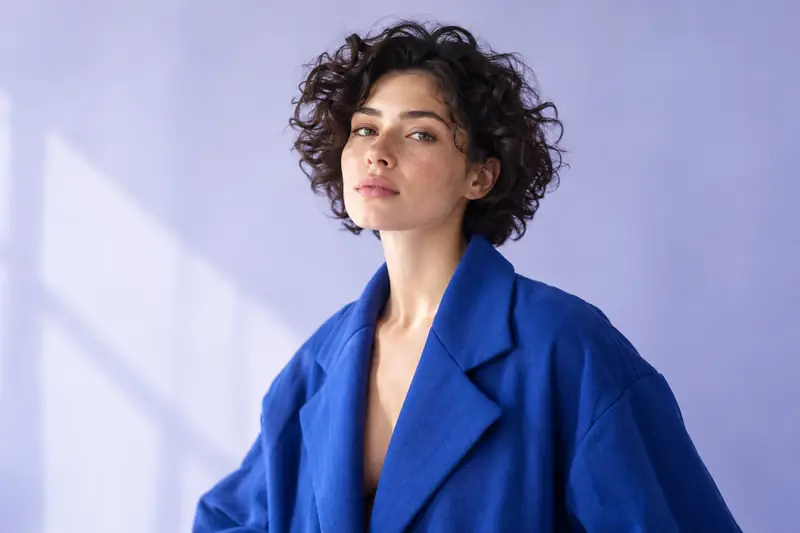 Editorial portrait of a woman in a cobalt jacket against lilac background